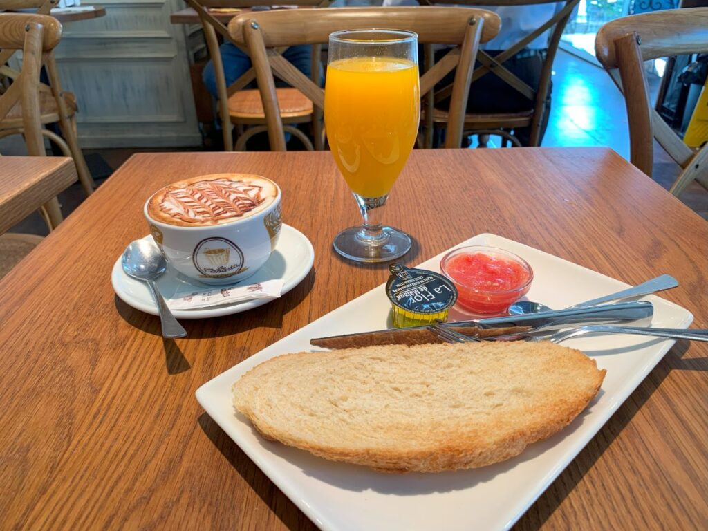 Spanish breakfast - pan con tomate. There is also a coffee and an orange juice on a table.