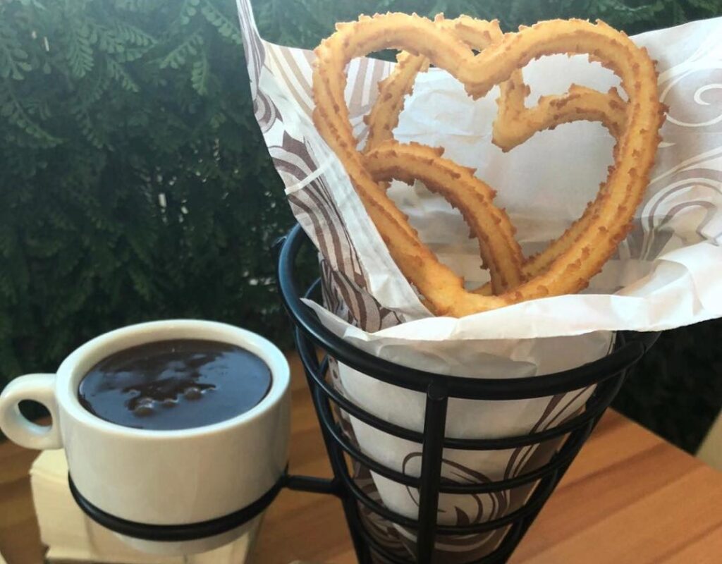 Spanish Churros sided by thick chocolate in a mug.