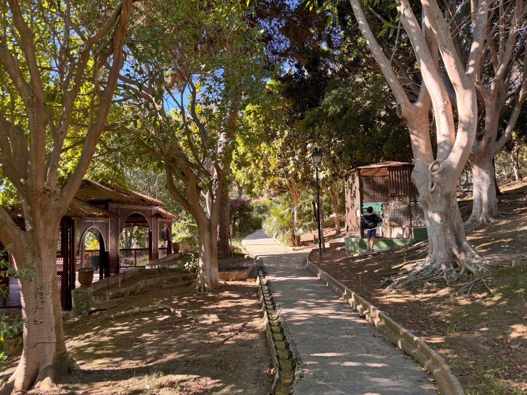 A path on the upper area of the botanical garden, with a bird cage on the right and one of the viewpoints on the left.