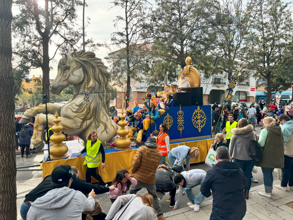 One of the 3 Kings' float, candies in the air and people collecting candies.